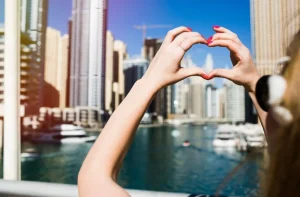 lady-with-red-nails-shows-heart-with-her-fingers-before-skyscrapers